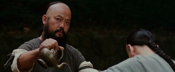 Movie still from “Crouching Tiger, Hidden Dragon” (2000), directed by Ang Lee – A man with a beard is holding a tea pot; Close Up shot, Over the shoulder angle