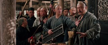 Movie still from “Crouching Tiger, Hidden Dragon” (2000), directed by Ang Lee – A group of men standing around a table with food; Medium shot, Over the shoulder angle