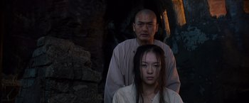 Movie still from “Crouching Tiger, Hidden Dragon” (2000), directed by Ang Lee – A man and a woman standing next to each other in front of a stone wall; Medium shot, Low angle