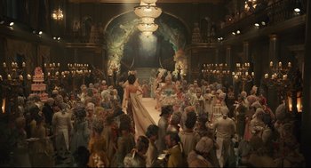 Movie still from “Cruella” (2021), directed by Craig Gillespie – A crowd of people in a large room with a large chandelier; Extreme Wide shot, High angle