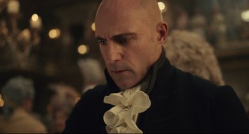 Movie still from “Cruella” (2021), directed by Craig Gillespie – A man with bald head wearing a black jacket; Close Up shot, Over the shoulder angle