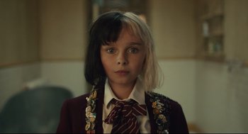 Movie still from “Cruella” (2021), directed by Craig Gillespie – A young girl wearing a suit and a tie; Close Up shot, Over the shoulder angle