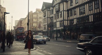 Movie still from “Cruella” (2021), directed by Craig Gillespie – A woman walking down the street in front of a building; Wide shot, Low angle
