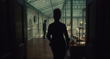 Movie still from “Cruella” (2021), directed by Craig Gillespie – A woman is walking in a dark room; Wide shot, Low angle