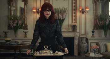 Movie still from “Cruella” (2021), directed by Craig Gillespie – A woman with red hair holding a tray of food; Medium shot, Low angle
