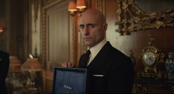 Movie still from “Cruella” (2021), directed by Craig Gillespie – A man in a suit and tie holding a briefcase; Close Up shot, Over the shoulder angle