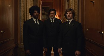 Movie still from “Cruella” (2021), directed by Craig Gillespie – A group of men standing next to each other in suits; Medium shot, Low angle