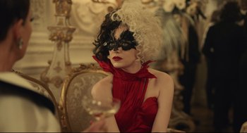 Movie still from “Cruella” (2021), directed by Craig Gillespie – A woman wearing a black mask and a red dress; Close Up shot, Over the shoulder angle