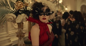 Movie still from “Cruella” (2021), directed by Craig Gillespie – A woman in a red dress wearing a black mask; Close Up shot, Over the shoulder angle