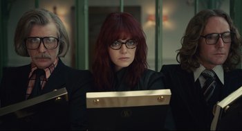 Movie still from “Cruella” (2021), directed by Craig Gillespie – A woman with red hair and glasses looking at the camera; Medium shot, Low angle