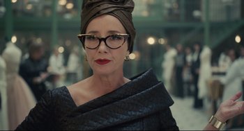 Movie still from “Cruella” (2021), directed by Craig Gillespie – A person wearing glasses and a turban; Close Up shot, Over the shoulder angle