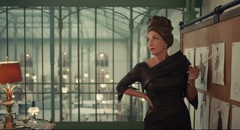 Movie still from “Cruella” (2021), directed by Craig Gillespie – A woman in a black dress and a head scarf; Medium shot, Over the shoulder angle