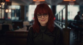 Movie still from “Cruella” (2021), directed by Craig Gillespie – A woman with red hair wearing glasses and a black shirt; Close Up shot, Low angle