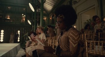 Movie still from “Cruella” (2021), directed by Craig Gillespie – A group of people sitting in a room with papers; Medium shot, Over the shoulder angle