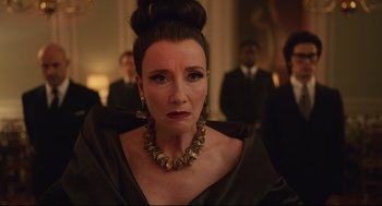 Movie still from “Cruella” (2021), directed by Craig Gillespie – A woman in a black dress and a gold necklace; Close Up shot, Over the shoulder angle