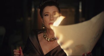 Movie still from “Cruella” (2021), directed by Craig Gillespie – A woman in a black dress looking at a paper; Close Up shot, Over the shoulder angle