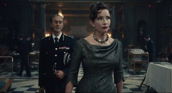 Movie still from “Cruella” (2021), directed by Craig Gillespie – A man and a woman standing next to each other; Medium shot, Low angle