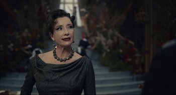 Movie still from “Cruella” (2021), directed by Craig Gillespie – A woman wearing a dress and a necklace looking to the side; Close Up shot, Over the shoulder angle