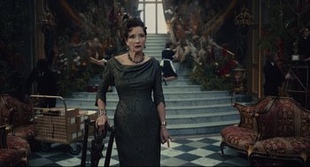 Movie still from “Cruella” (2021), directed by Craig Gillespie – A woman in a black dress standing in front of a staircase; Medium shot, Low angle
