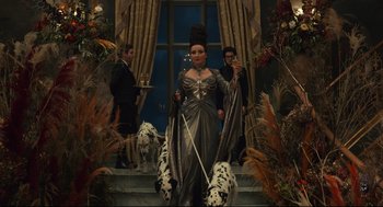 Movie still from “Cruella” (2021), directed by Craig Gillespie – A woman in a silver dress holding a pair of swords; Medium shot, Low angle