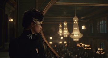 Movie still from “Cruella” (2021), directed by Craig Gillespie – A woman in a black dress standing next to a stage; Medium shot, Low angle