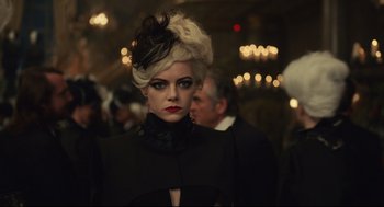 Movie still from “Cruella” (2021), directed by Craig Gillespie – A woman in a black coat and a black hat; Close Up shot, Low angle