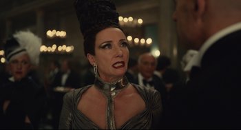 Movie still from “Cruella” (2021), directed by Craig Gillespie – A woman in a silver dress and a black hat; Close Up shot, Over the shoulder angle