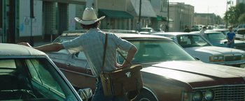 Movie still from “Dallas Buyers Club” (2013), directed by Jean-Marc Vallée – A man in a cowboy hat is holding a brown bag; Medium shot, Low angle