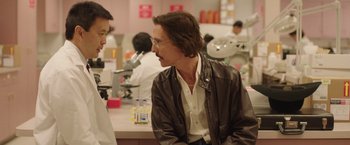 Movie still from “Dallas Buyers Club” (2013), directed by Jean-Marc Vallée – A man in a brown jacket talking to another man in a lab; Medium shot, Over the shoulder angle