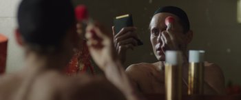 Movie still from “Dallas Buyers Club” (2013), directed by Jean-Marc Vallée – A man is looking in the mirror while holding a book; Close Up shot, Over the shoulder angle