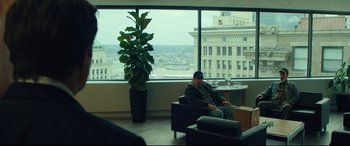 Movie still from “Dark Waters” (2019), directed by Todd Haynes – A man sitting in a chair in front of a large window; Wide shot, Over the shoulder angle