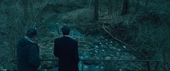 Movie still from “Dark Waters” (2019), directed by Todd Haynes – A man in a black suit looking over a stream; Extreme Wide shot, High angle