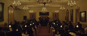 Movie still from “Dark Waters” (2019), directed by Todd Haynes – A group of people sitting at tables in a room; Extreme Wide shot, High angle