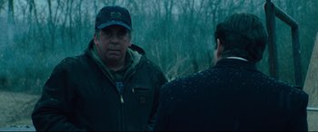 Movie still from “Dark Waters” (2019), directed by Todd Haynes – A man wearing a hat and a jacket standing next to another man in a forest; Medium shot, Over the shoulder angle