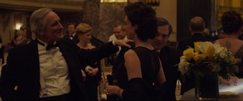 Movie still from “Dark Waters” (2019), directed by Todd Haynes – A woman in a black dress standing next to a man in a black suit; Medium shot, Over the shoulder angle