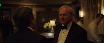 Movie still from “Dark Waters” (2019), directed by Todd Haynes – A man in a tuxedo standing next to another man in a suit; Medium shot, Over the shoulder angle