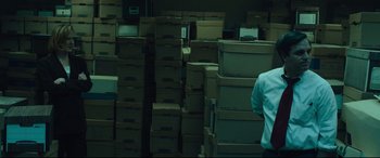 Movie still from “Dark Waters” (2019), directed by Todd Haynes – A man standing in front of stacks of cardboard boxes; Wide shot, Over the shoulder angle