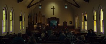 Movie still from “Dark Waters” (2019), directed by Todd Haynes – A man is sitting in front of a microphone in front of a crowd of onlookers; Extreme Wide shot, Low angle