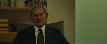 Movie still from “Dark Waters” (2019), directed by Todd Haynes – An older man wearing a suit and tie sitting in a chair; Close Up shot, Over the shoulder angle