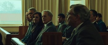 Movie still from “Dark Waters” (2019), directed by Todd Haynes – A group of people sitting in front of a curtain; Medium shot, Over the shoulder angle