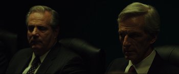 Movie still from “Dark Waters” (2019), directed by Todd Haynes – Two men in suits sitting next to each other in a dark room; Close Up shot, Over the shoulder angle