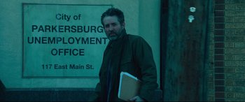 Movie still from “Dark Waters” (2019), directed by Todd Haynes – A man holding a book standing in front of a building; Medium shot, Low angle