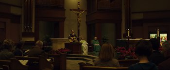 Movie still from “Dark Waters” (2019), directed by Todd Haynes – A group of people sitting in a room with a cross on the wall; Extreme Wide shot, Low angle