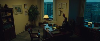 Movie still from “Dark Waters” (2019), directed by Todd Haynes – A man sitting at a desk in front of a large window; Wide shot, High angle