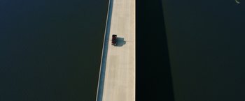 Movie still from “Deepwater Horizon” (2016), directed by Peter Berg – An aerial view of a truck driving down a bridge; Extreme Wide shot, Overhead angle