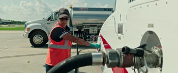 Movie still from “Deepwater Horizon” (2016), directed by Peter Berg – A man in an orange and white vest filling up a tanker truck; Medium shot, Low angle