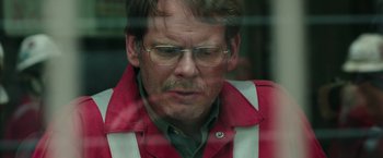 Movie still from “Deepwater Horizon” (2016), directed by Peter Berg – A person wearing glasses and a red jacket; Close Up shot, Over the shoulder angle