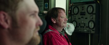 Movie still from “Deepwater Horizon” (2016), directed by Peter Berg – A man sitting next to another man wearing glasses; Close Up shot, Over the shoulder angle