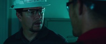 Movie still from “Deepwater Horizon” (2016), directed by Peter Berg – A man wearing a hard hat talking to another man; Close Up shot, Over the shoulder angle