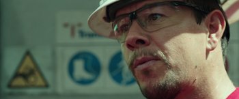 Movie still from “Deepwater Horizon” (2016), directed by Peter Berg – A person wearing glasses and a hat; Close Up shot, Low angle
